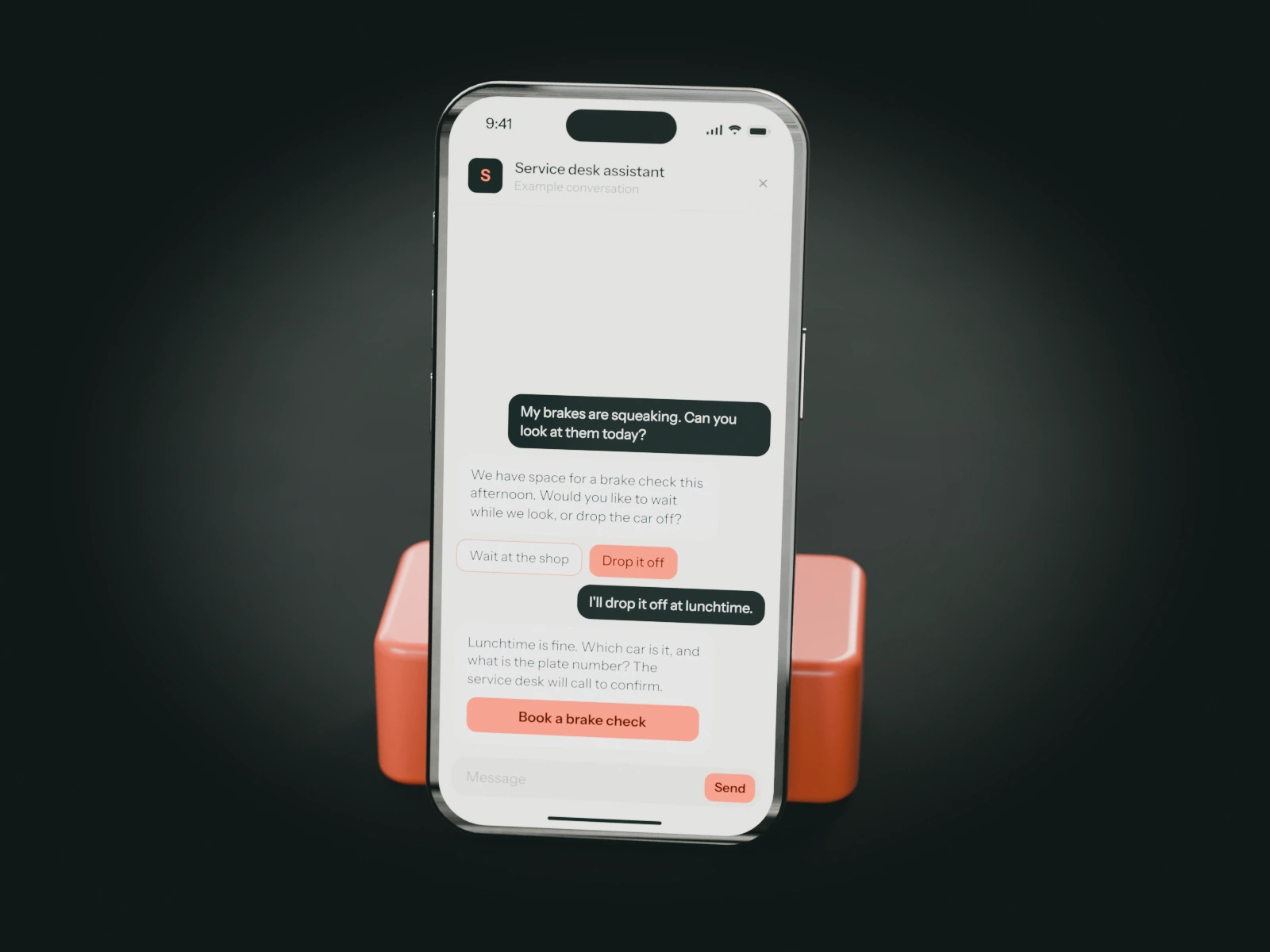 A phone on a coral stand showing an example chat with an auto repair shop's service desk assistant: a driver with squeaking brakes asks for a check today and will drop the car off at lunchtime.
