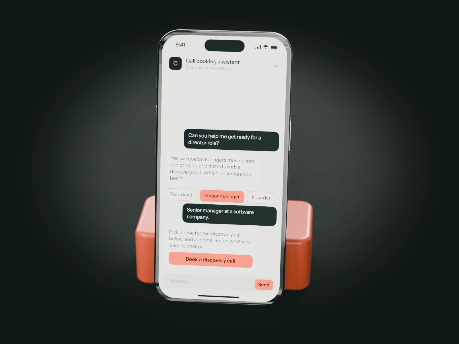 A phone on a coral stand showing an example chat with a leadership coach's call booking assistant: a senior manager asks about coaching for a director role and is offered a discovery call.