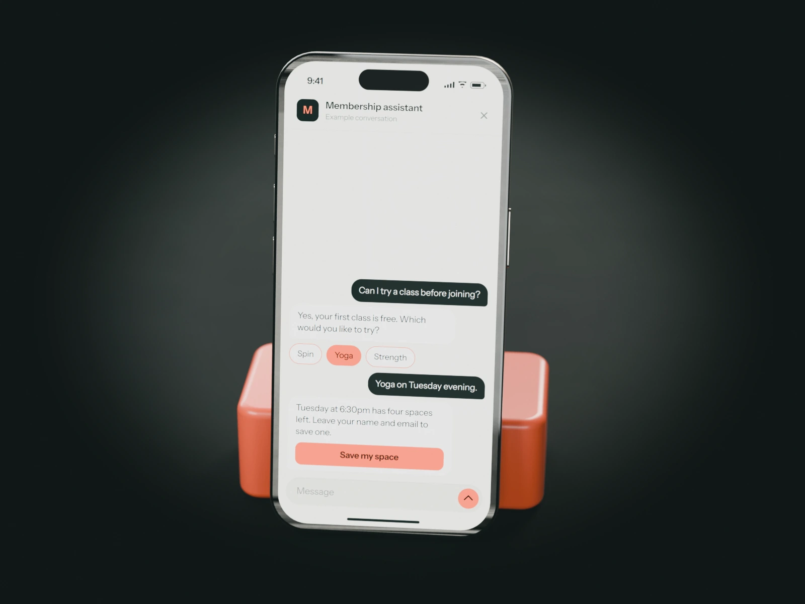 A phone on a coral stand showing an example chat with a fitness studio's membership assistant: a visitor books a free trial yoga class on Tuesday.