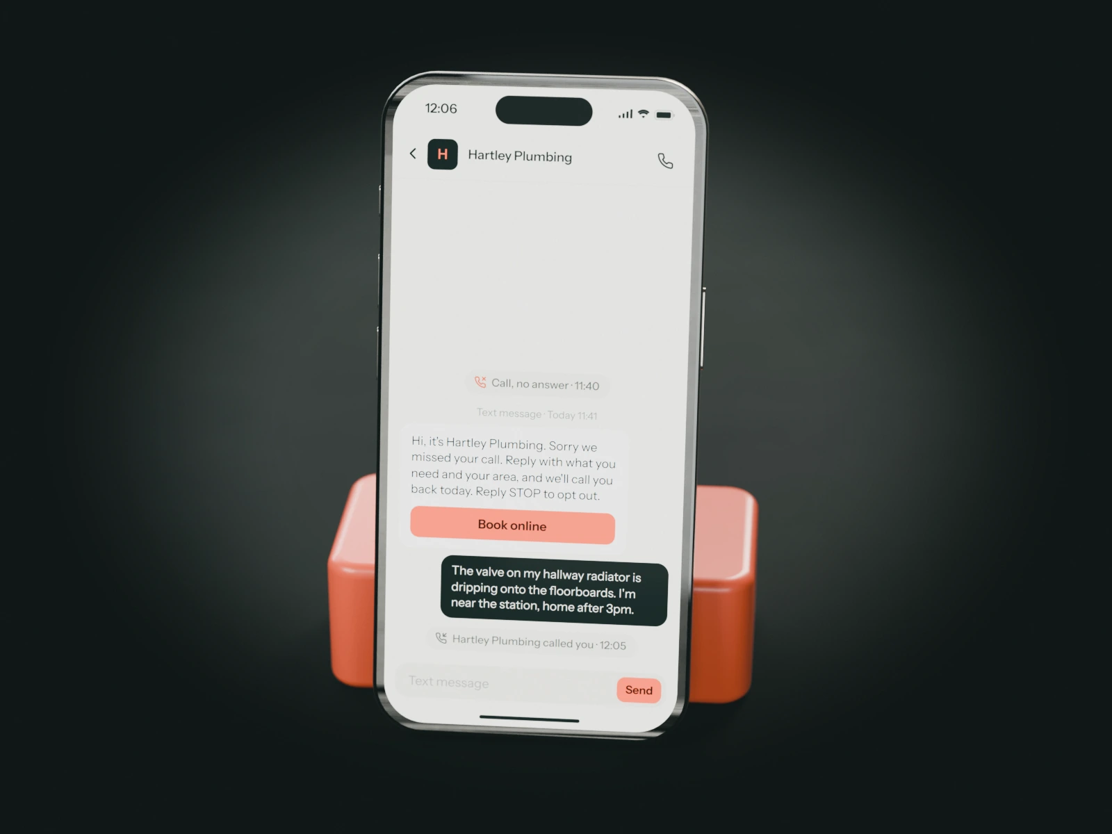 A phone on a coral stand showing the text Hartley Plumbing sent a minute after a missed call, the caller's reply about a dripping radiator valve and the call back.