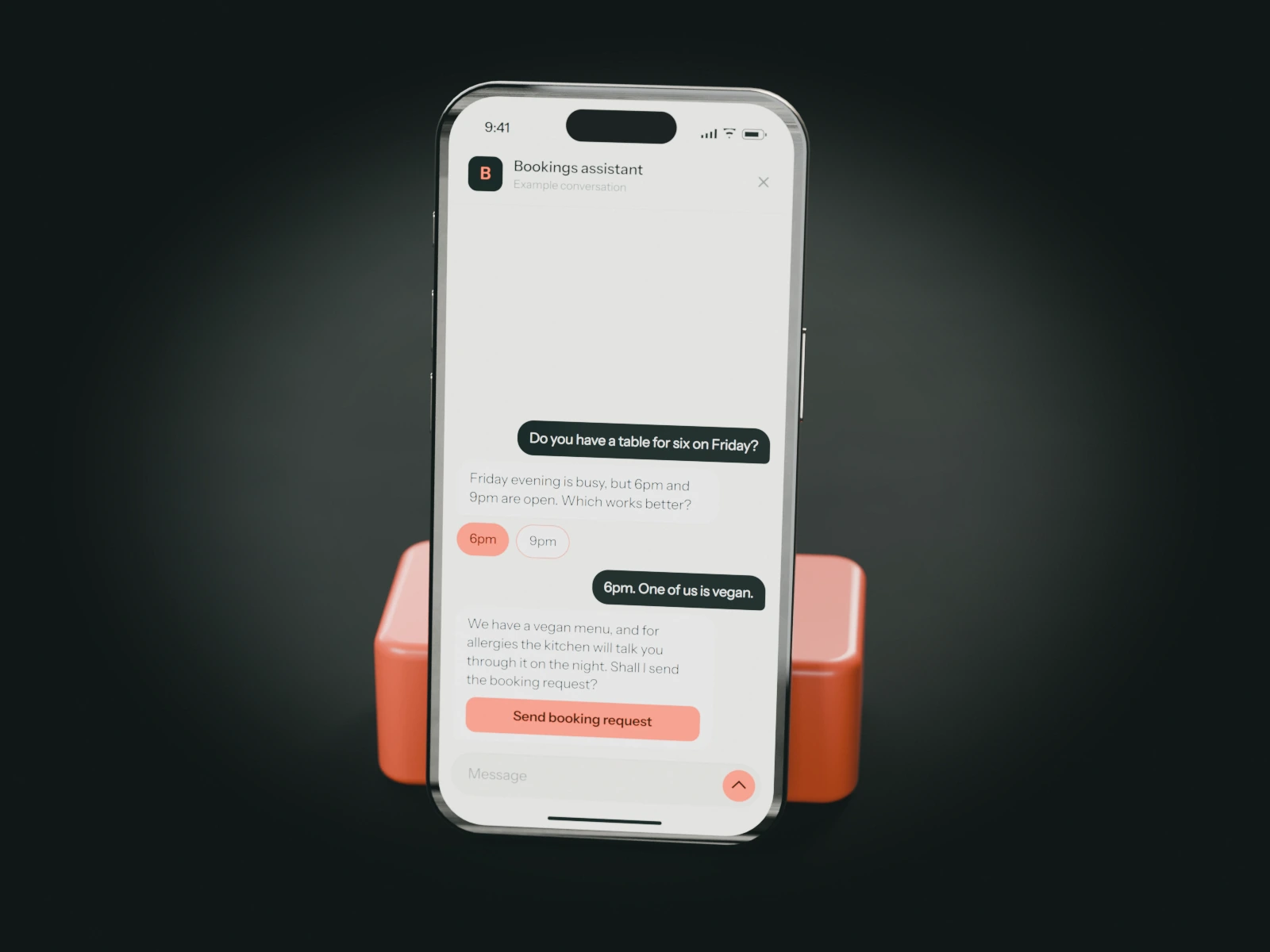 A phone on a coral stand showing an example chat with a restaurant's bookings assistant: a guest asks for a table for six and mentions a vegan diner.